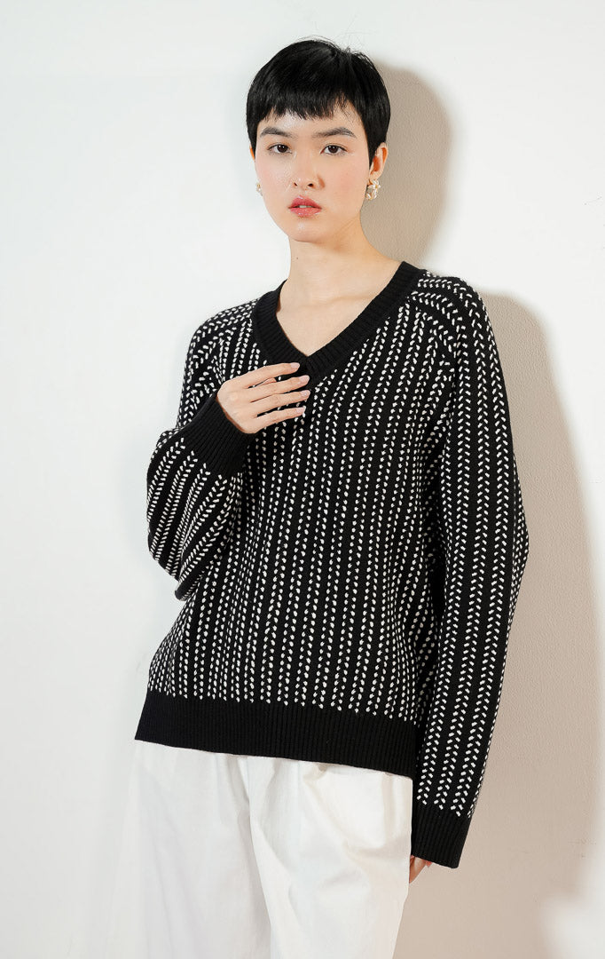Model wanita mengenakan Brooke Sweater warna black, baju atasan sweater rajut wanita lengan panjang berwarna hitam dengan detail motif tekstur putih kontras yang modis.