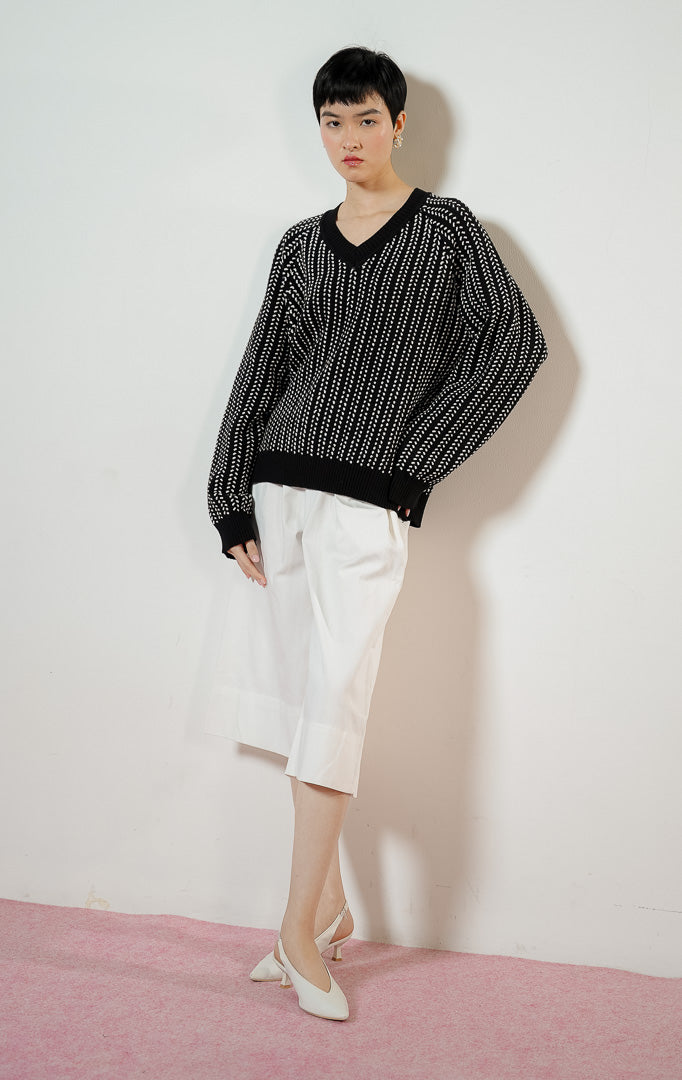 Model wanita mengenakan Brooke Sweater warna black, baju atasan sweater rajut wanita lengan panjang berwarna hitam dengan detail motif tekstur putih kontras yang modis.