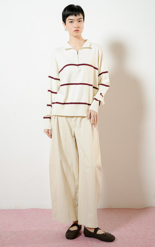 Model wanita mengenakan Jayce Half-Zip Striped Pullover Sweater warna ivory, baju atasan sweater rajut wanita lengan panjang warna putih gading motif garis marun dengan kerah ritsleting half-zip.
