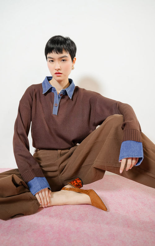Model wanita berpose duduk mengenakan Susie Denim Collar Cuff Knit Sweater warna dark brown, atasan baju sweater rajut wanita berwarna cokelat tua dengan kerah kemeja dan manset bahan jeans denim biru.