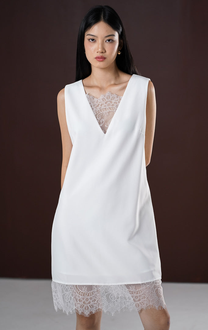 Dress pendek wanita Sydney warna putih bersih tanpa lengan menampilkan kerah V-neck dengan aksen brokat lace transparan di bagian dada dan keliman bawah dress.