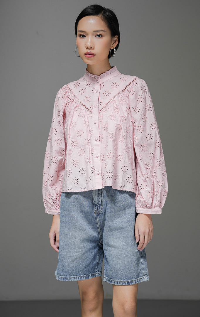 Atasan blouse wanita Sylvia Top warna pink bahan eyelet bordir dengan detail kerah frill rumbai dan kancing depan bungkus yang manis.