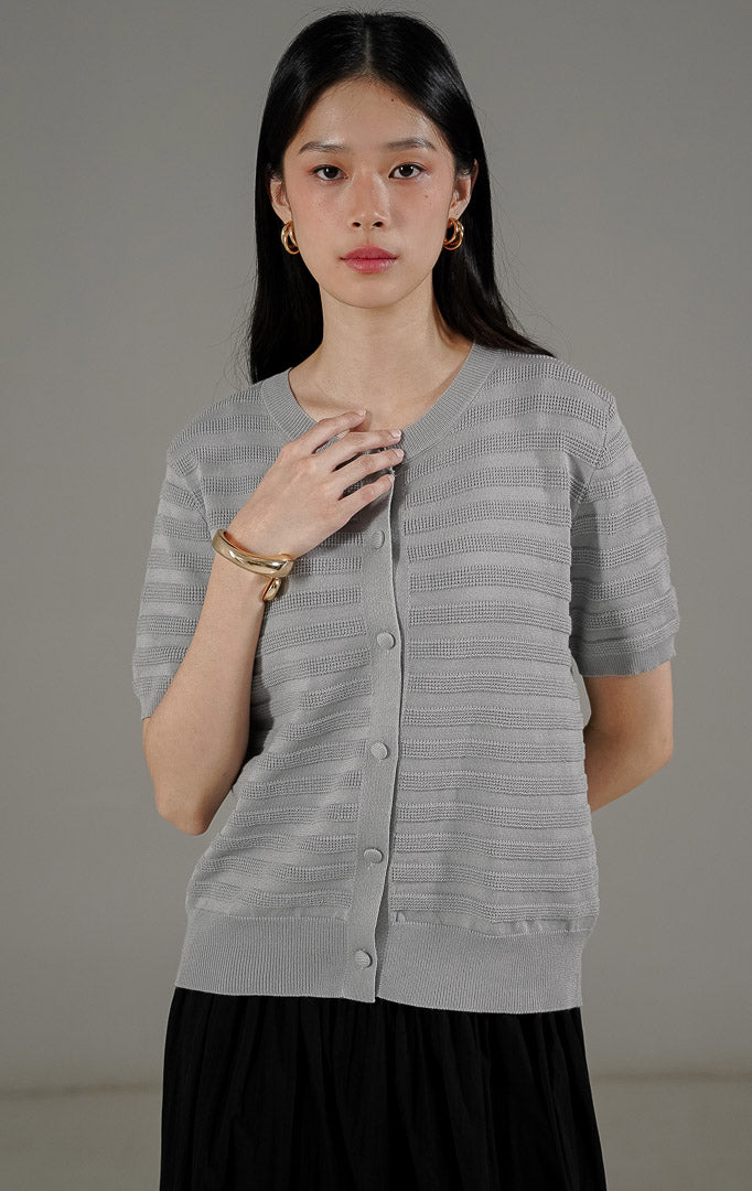Annalina Cardigan Grey dari This Is April, atasan rajut lengan pendek warna abu-abu dengan motif garis benang timbul dan kancing depan aktif.