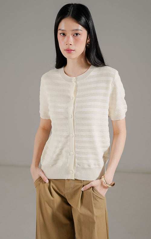 Annalina Cardigan Ivory dari This Is April, atasan rajut lengan pendek warna putih ivory dengan detail garis tekstur benang timbul dan kancing depan.