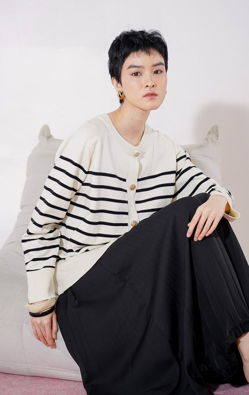 Tampak depan This Is April Aurelie Cardigan warna ivory, cardigan lengan panjang dengan motif garis hitam horizontal, kerah bulat, dan detail kancing depan berwarna emas