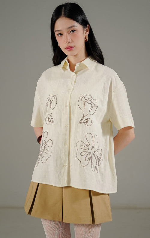Bellamy Top Ivory dari This Is April, kemeja oversize warna putih ivory dengan motif bunga (floral) minimalis dan detail kancing depan.