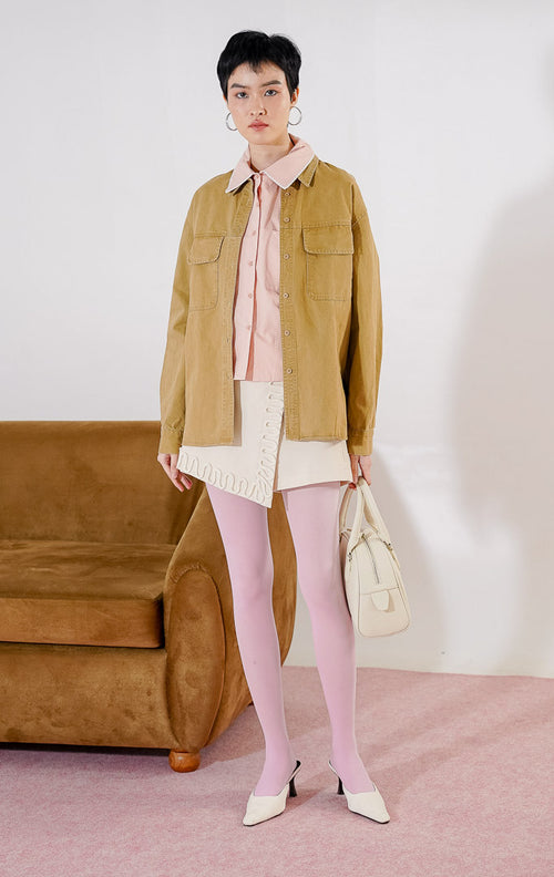 Kemeja wanita lengan panjang Dahlia Top dari This Is April berwarna khaki berbahan katun twill dengan dua kantong dada fungsional dan kancing depan, digantung di rak pakaian.