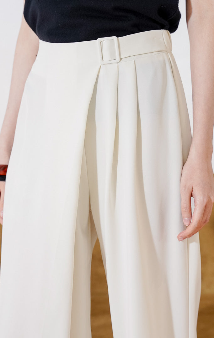celana panjang wanita berbahan katun campuran This Is April Ellen Pants warna ivory, berpotongan lurus dengan detail sabuk built-in di bagian depan, lipit asimetris, dan karet pinggang belakang