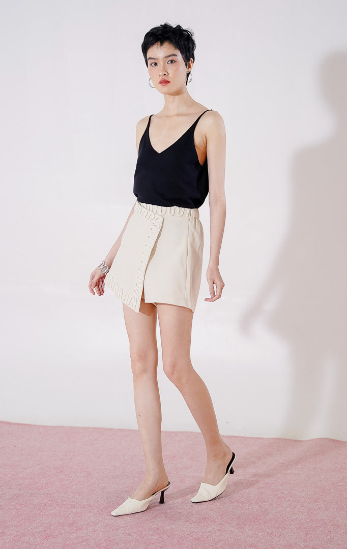 Rok celana wanita This Is April Elvio Skort warna ivory, dengan karet pinggang di bagian belakang, potongan depan asimetris bergaya wrap, dan detail lis tali bergelombang di sepanjang tepinya