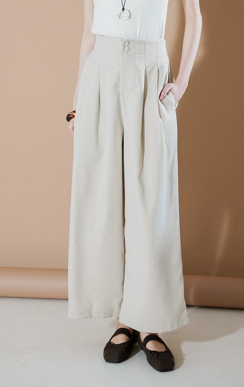 Endellion Pants Beige dari This Is April, celana panjang tailored wanita warna krem dengan detail dua kancing di pinggang, lipit depan (pleated), dan bahan katun terstruktur.