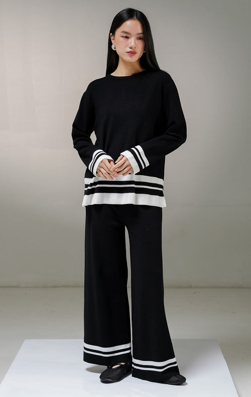 Setelan one set wanita This Is April Espera Set warna hitam, terdiri dari atasan sweater rajut lengan panjang kerah bulat dan celana panjang rajut dengan detail aksen garis horisontal warna putih di bagian ujung bawah.
