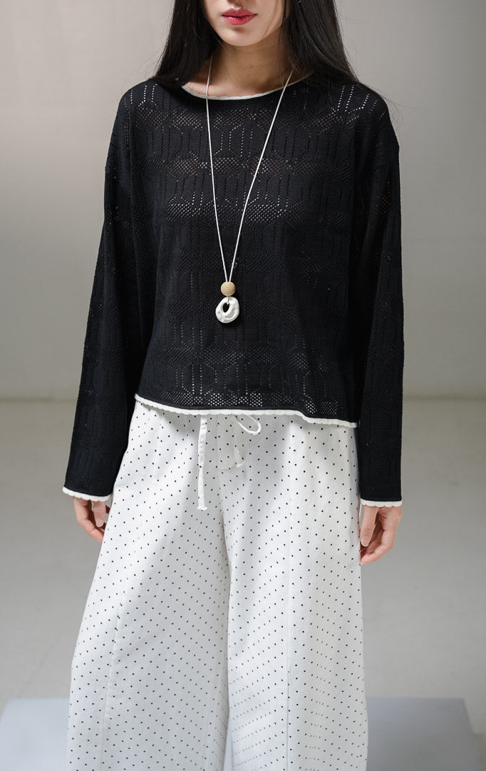 Atasan sweater rajut lengan panjang wanita This Is April Evie Sweater warna hitam, model jaring mesh knit transparan dengan aksen list tipis warna putih tulang pada kerah bulat dan tepian bawah.