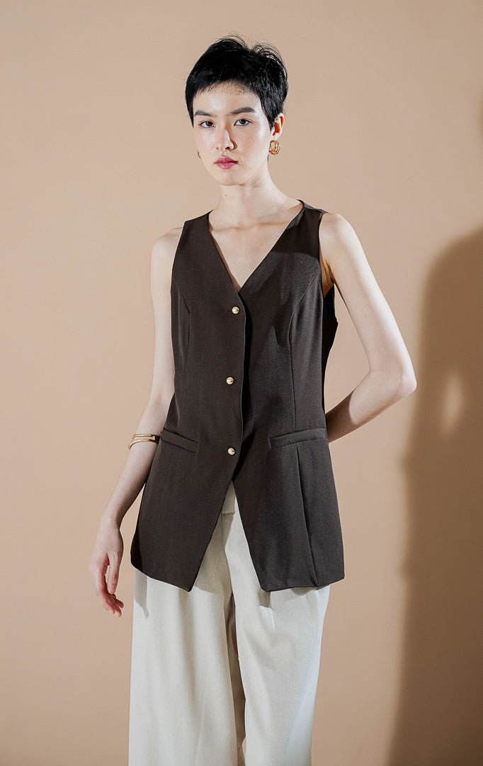 Laurence Vest Dark Brown dari This Is April, rompi panjang tanpa lengan wanita warna cokelat tua dengan detail kancing emas dan saku dekoratif