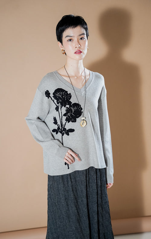 Lulie Sweater Grey dari This Is April, sweater rajut leher V-neck warna abu-abu dengan detail bordir bunga mawar hitam yang besar di bagian depan.