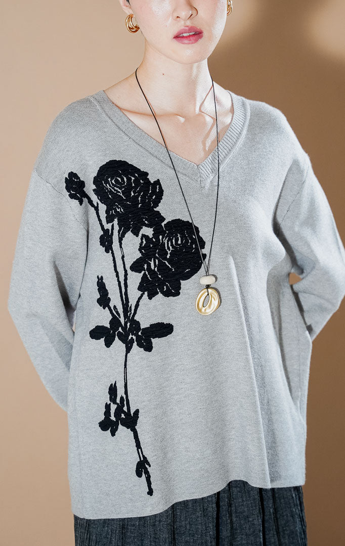 Lulie Sweater Grey dari This Is April, sweater rajut leher V-neck warna abu-abu dengan detail bordir bunga mawar hitam yang besar di bagian depan.