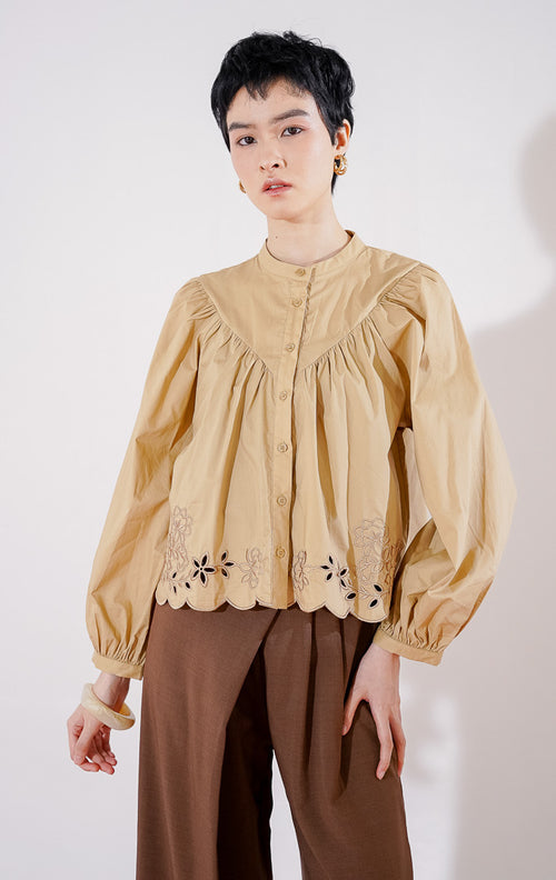 Blouse wanita This Is April Marvie Top warna khaki dengan kerah shanghai, lengan panjang bervolume, detail jahitan yoke di dada, dan aksen bordir eyelet floral pada ujung bawah bergelombang