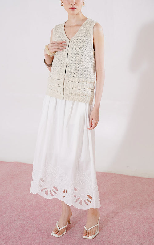 Tampak depan This Is April Pierre Vest warna ivory, rompi rajut crochet tanpa lengan dengan pola rajutan kait bertekstur, kerah V-neck, dan kancing depan