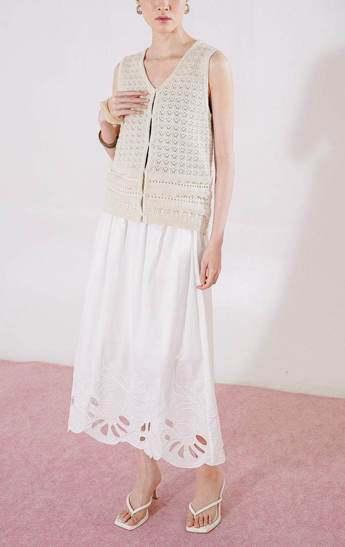Tampak depan This Is April Pierre Vest warna ivory, rompi rajut crochet tanpa lengan dengan pola rajutan kait bertekstur, kerah V-neck, dan kancing depan