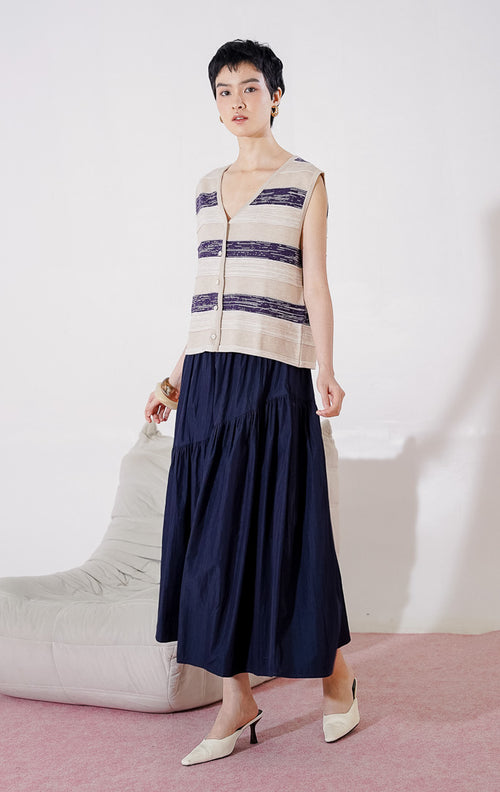 Tampak depan This Is April Sydney Vest warna khaki, rompi rajut tanpa lengan dengan motif garis horizontal marled, kerah V-neck, dan kancing depan.