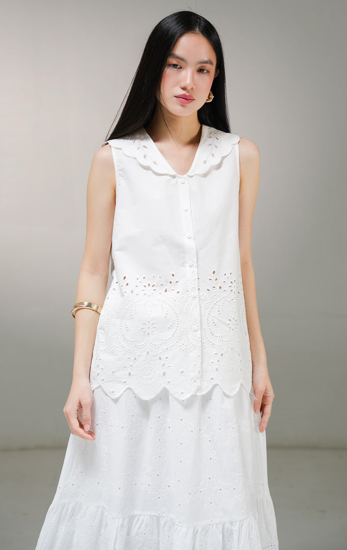 Atasan blouse tanpa lengan wanita This Is April Therine Top warna putih, model sleeveless shirt dengan kerah v-neck lebar bergelombang scalloped dan detail bordir bolong katbol di bagian bawah.