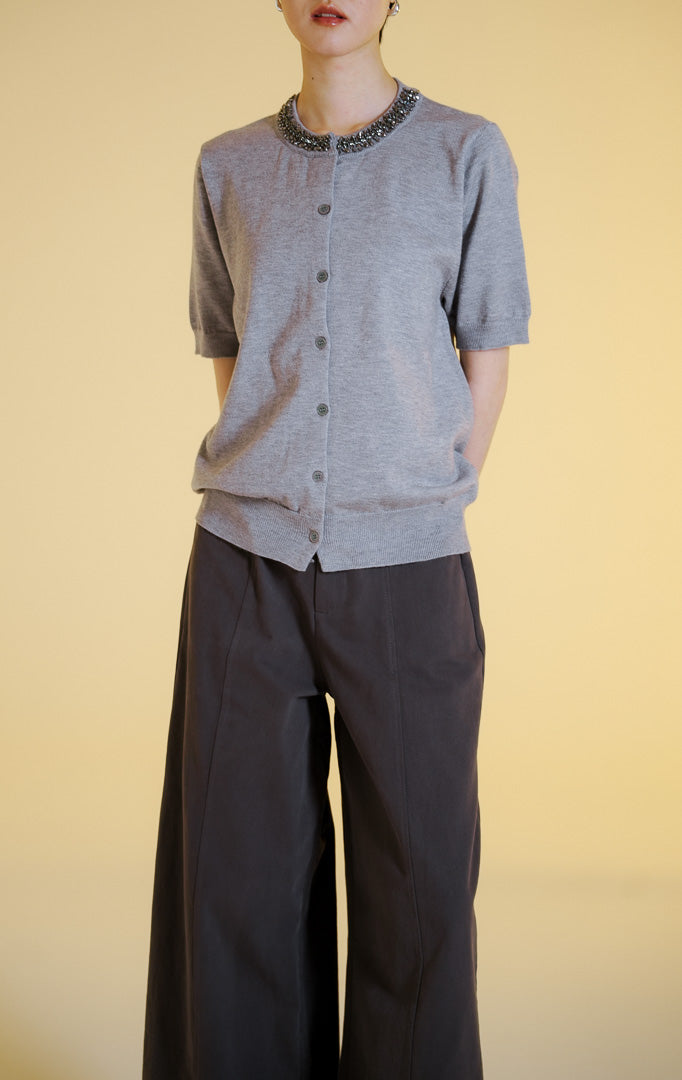 Pakaian wanita model atasan rajut cardigan lengan pendek dengan kancing depan dan hiasan permata di bagian kerah bulat (gemstone neckline short sleeve knit top) warna abu-abu muda Alveria Top untuk gaya kantor dan kasual anggun.