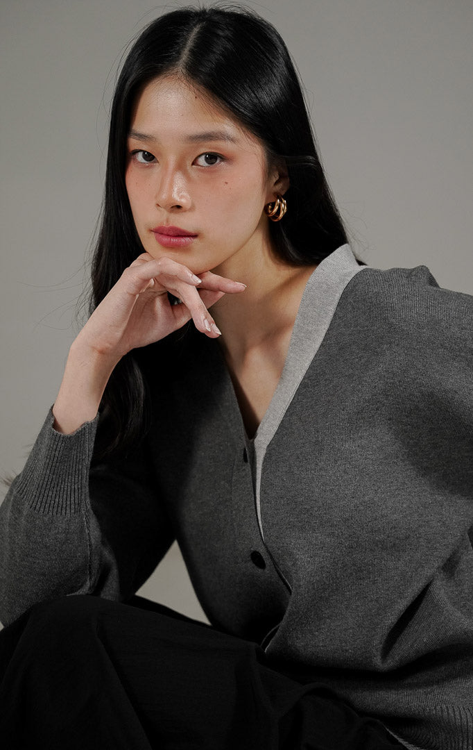 Blaise Cardigan Dark Grey dari This Is April, cardigan rajut V neck warna abu abu tua dengan kancing depan dan detail rib di ujung lengan.