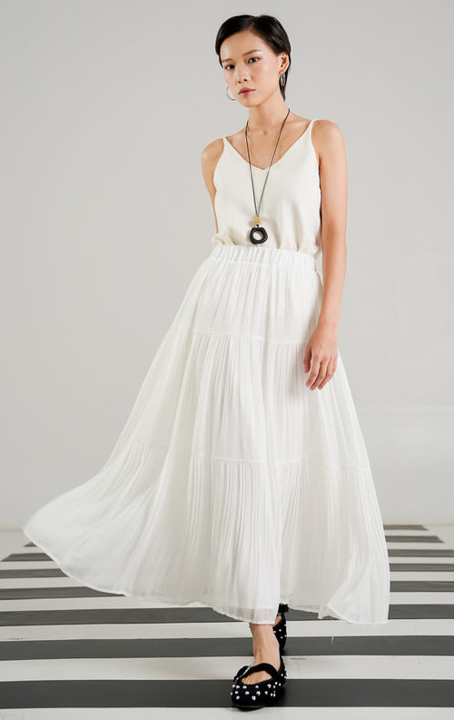 Rok panjang (maxi skirt) wanita warna putih (white) dengan detail lipit (pleated), potongan bersusun atau berundak (tiered), dan karet pinggang elastis dari This Is April.