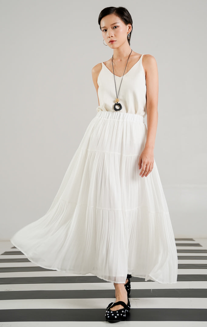 Rok panjang (maxi skirt) wanita warna putih (white) dengan detail lipit (pleated), potongan bersusun atau berundak (tiered), dan karet pinggang elastis dari This Is April.