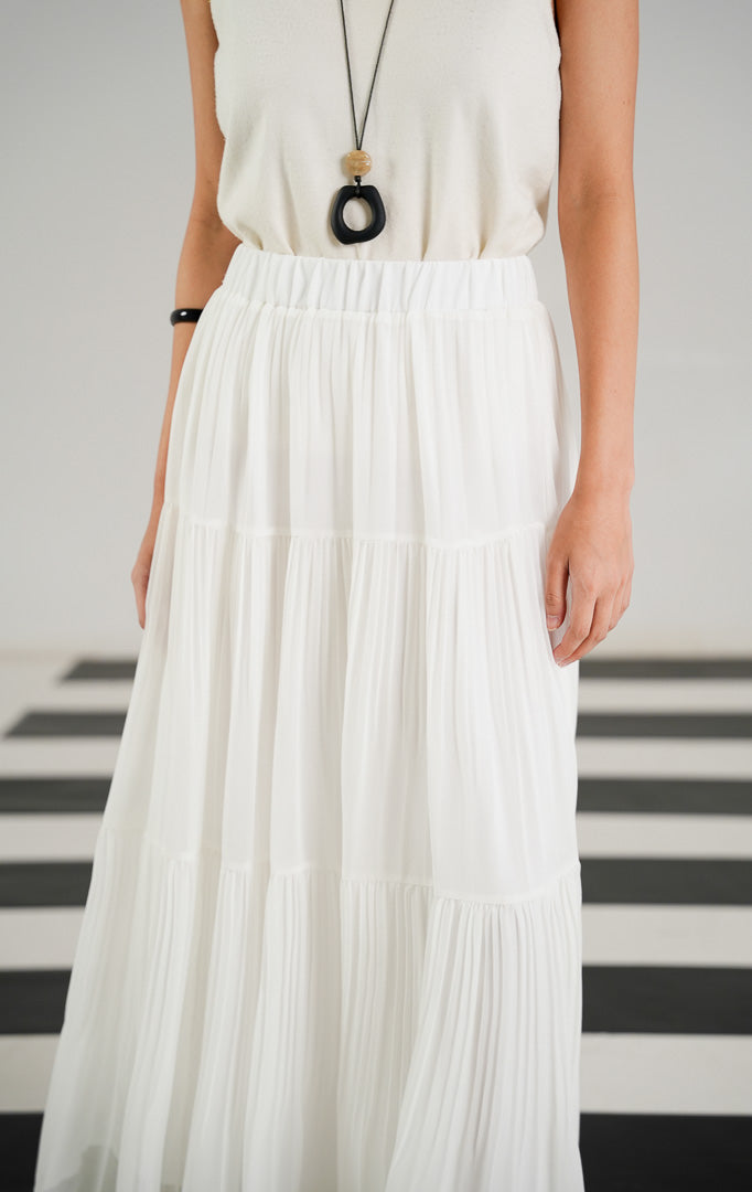 Rok panjang (maxi skirt) wanita warna putih (white) dengan detail lipit (pleated), potongan bersusun atau berundak (tiered), dan karet pinggang elastis dari This Is April.