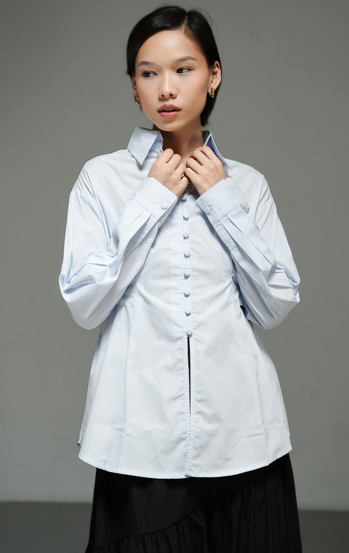 Atasan wanita model kemeja katun lengan panjang warna biru muda (light blue corseted waist shirt top) Effie Top dengan potongan korset yang memberikan siluet modern dan rapi.