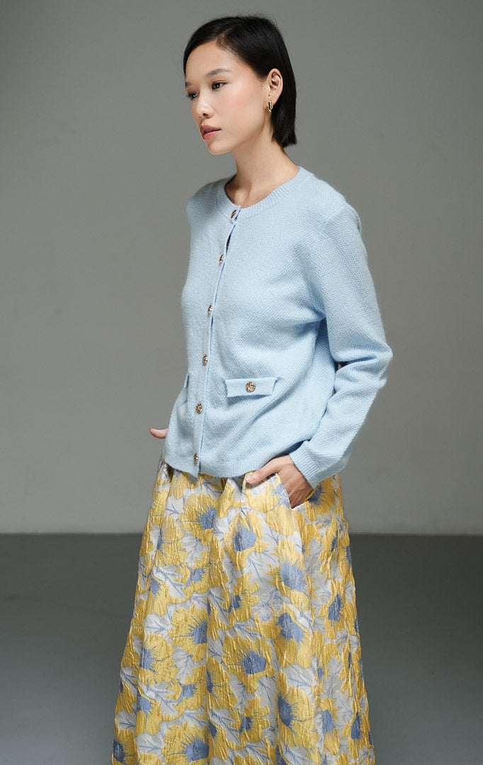 Atasan wanita model cardigan rajut katun bertekstur warna biru muda (light blue ornate textured cotton knit cardigan) Elaris Cardigan dengan detail kancing depan serta saku dekoratif bergaya utilitas yang chic.
