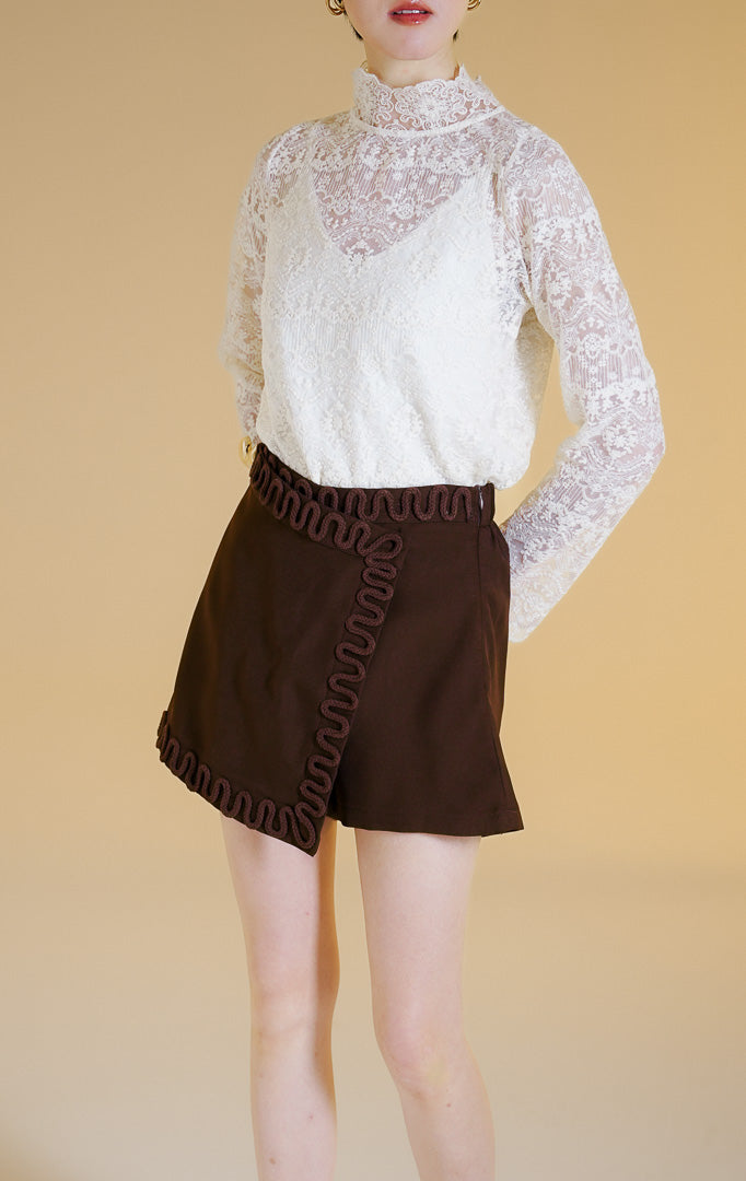 Pakaian wanita model celana rok mini gaya rapi (tailored skort) dengan detail lis hiasan tali di sepanjang tepi (rope trim) warna cokelat tua Elvio Skort untuk gaya kasual chic yang elegan.