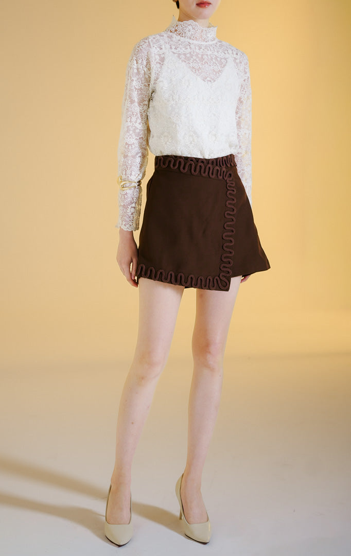Pakaian wanita model celana rok mini gaya rapi (tailored skort) dengan detail lis hiasan tali di sepanjang tepi (rope trim) warna cokelat tua Elvio Skort untuk gaya kasual chic yang elegan.