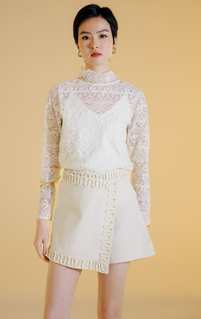 Pakaian wanita model celana rok mini gaya rapi (tailored skort) dengan detail lis hiasan tali di sepanjang tepi (rope trim) warna ivory Elvio Skort untuk gaya kasual chic yang elegan.