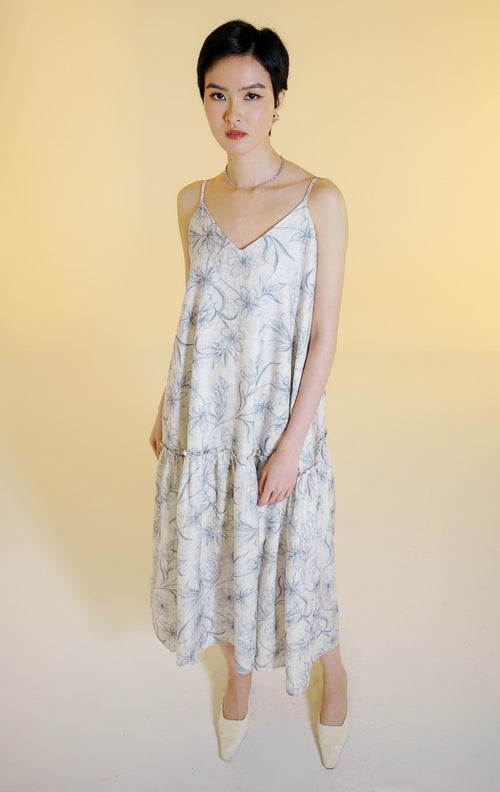 Pakaian wanita model gaun midi tali spageti motif bunga dengan detail kerutan ruffle seam (ruffle seam floral midi dress) warna abu-abu muda Fresla Dress untuk gaya kasual dan liburan.