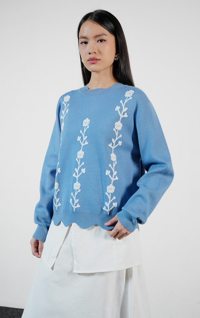 Atasan wanita model sweater rajut lengan panjang warna biru dengan detail hiasan bunga rajut dan potongan bawah bergelombang (blue crochet flower scallop knit sweater) Galina Sweater untuk gaya feminin harian.