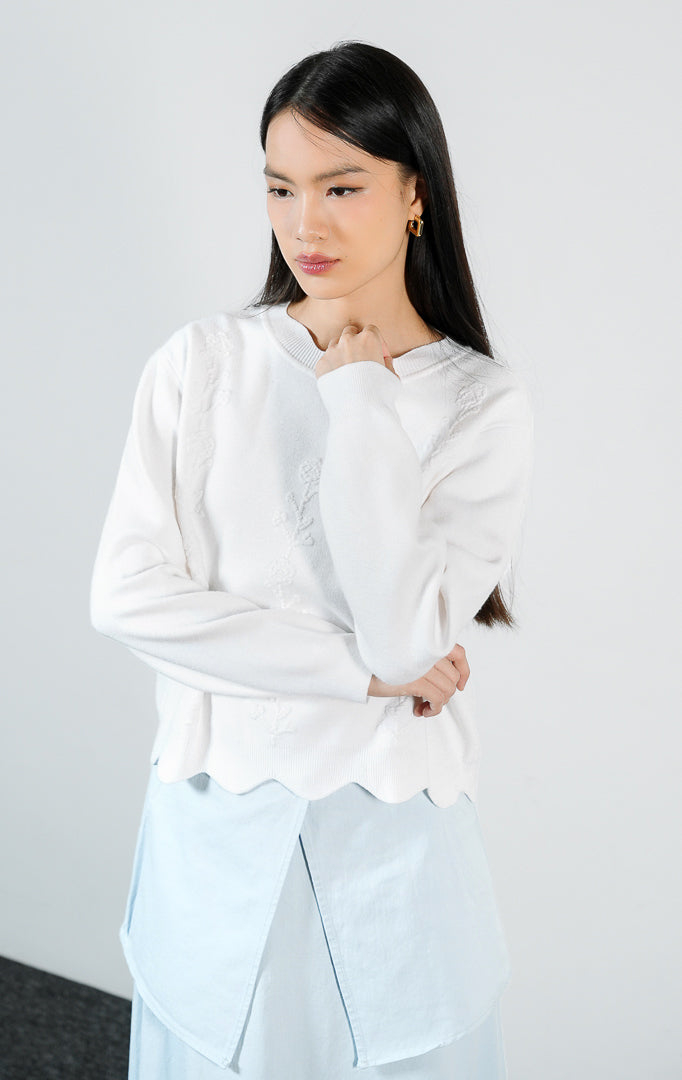 Atasan wanita model sweater rajut lengan panjang warna putih dengan detail hiasan bunga rajut dan potongan bawah bergelombang (white crochet flower scallop knit sweater) Galina Sweater untuk gaya kasual yang anggun.