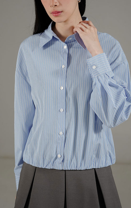 Hailee Top Baby Blue dari This Is April, kemeja stripe biru putih dengan detail kerah, kancing depan, dan ujung bawah karet (elastic hem).