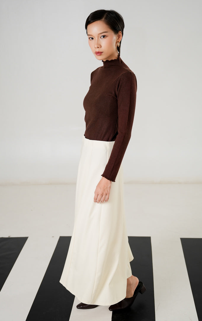 Rok midi wanita (midi skirt) warna cream (krem) berpotongan rapi dengan detail jahitan panel lurus dan resleting (zipper) tersembunyi dari This Is April.
