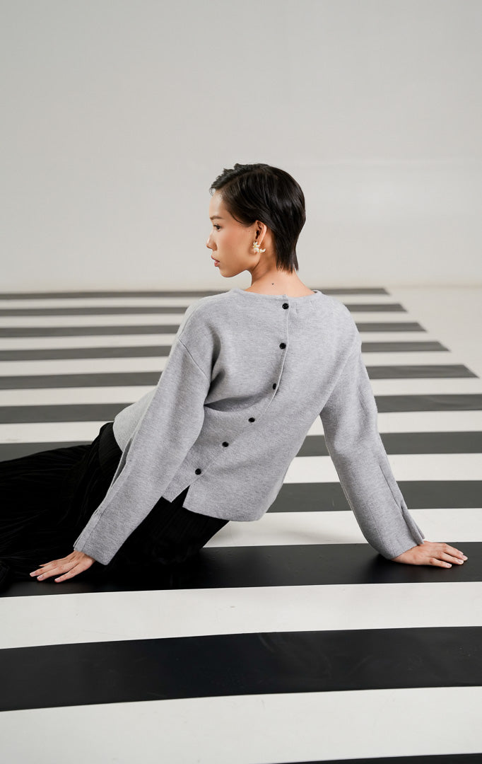 Atasan rajut wanita lengan panjang warna abu abu (grey) dengan kerah bulat dan detail deretan kancing kecil berwarna hitam di bagian tengah dari This Is April.