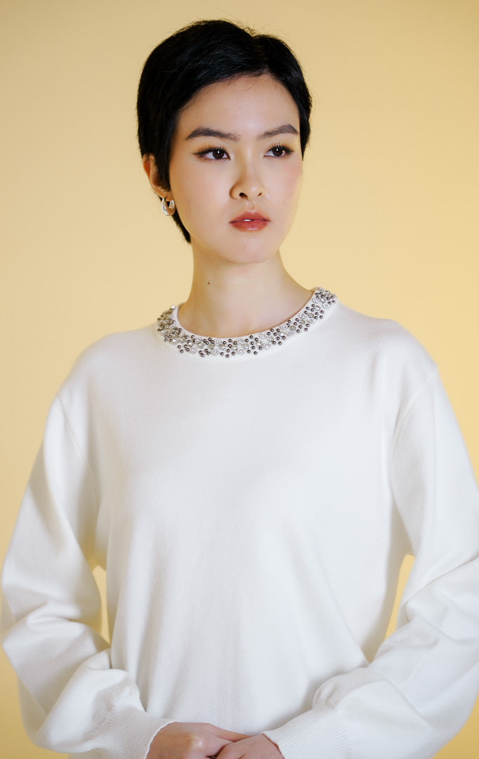Pakaian hangat wanita model sweter rajut lengan panjang dengan hiasan manik-manik di bagian kerah bulat (beaded neckline knit sweater) warna putih Luella Sweater untuk gaya kasual elegan.