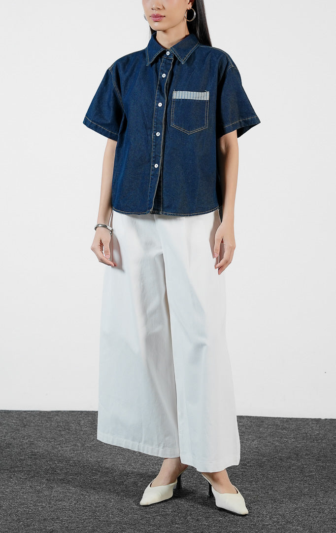 Pakaian wanita model kemeja denim pendek warna biru tua dengan detail saku dada beraksen garis (stripe-trimmed chest pocket shirt) Luniel Top untuk gaya kasual modern yang stylish.