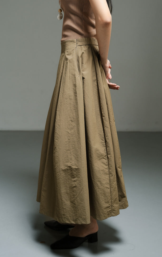 Rok panjang wanita model A-line warna hijau olive (olive parachute a-line skirt) Lyanna Skirt dengan bahan nilon parasut ringan, siluet bervolume dinamis, serta sentuhan gaya utilitas yang modern.