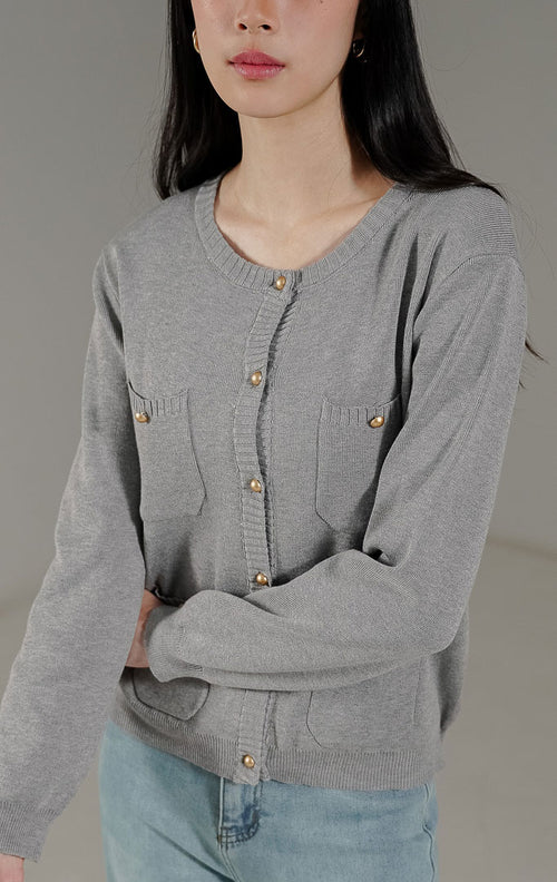 Meriya Cardigan Grey dari This Is April, cardigan rajut lengan panjang warna abu abu dengan detail 4 saku depan dan kancing emas yang elegan.