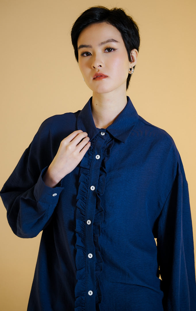 Pakaian wanita model kemeja lengan panjang berkerah dengan detail kerutan rempel di sepanjang kancing depan (dual-sided ruffled placket shirt) warna navy Mirena Top untuk gaya kantor dan kasual anggun.