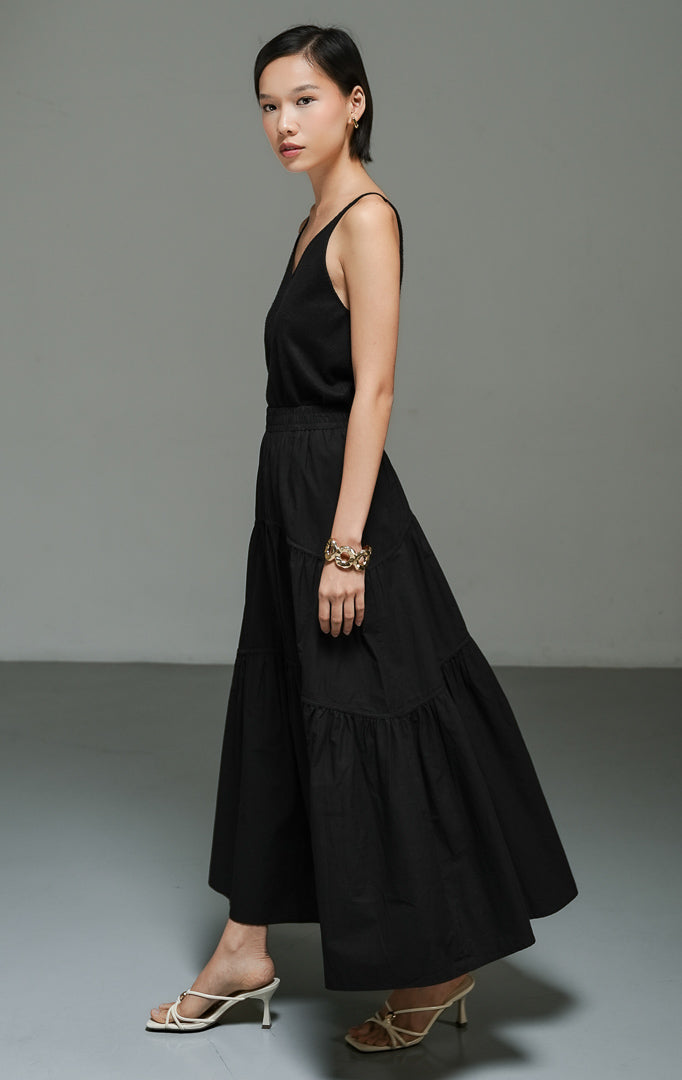 Rok panjang wanita model maxi flared warna hitam (black gathered flared maxi skirt) Okeanos Skirt dengan detail kerut bertingkat, bahan yang jatuh dengan lembut, serta tampilan elegan yang serbaguna.
