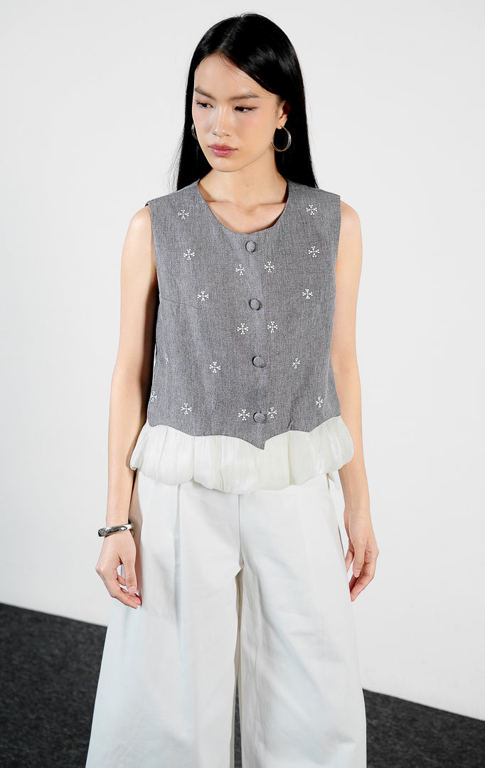 Pakaian wanita model rompi tanpa lengan motif salju dengan detail ujung kerut ruffle warna abu-abu (grey snowflake pattern ruffle hem vest) Ottila Vest untuk gaya kasual modern yang anggun.