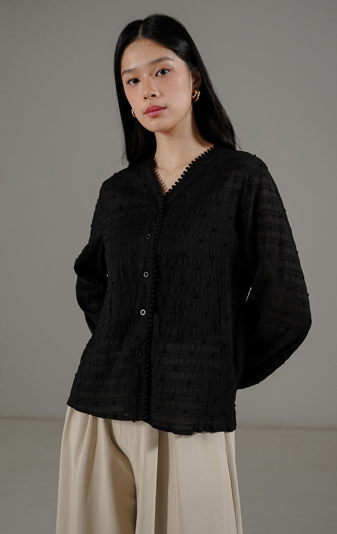 Palmer Top Black dari This Is April, blus lengan panjang warna hitam bahan sheer menerawang dengan detail bordir benang timbul dan kerah V.