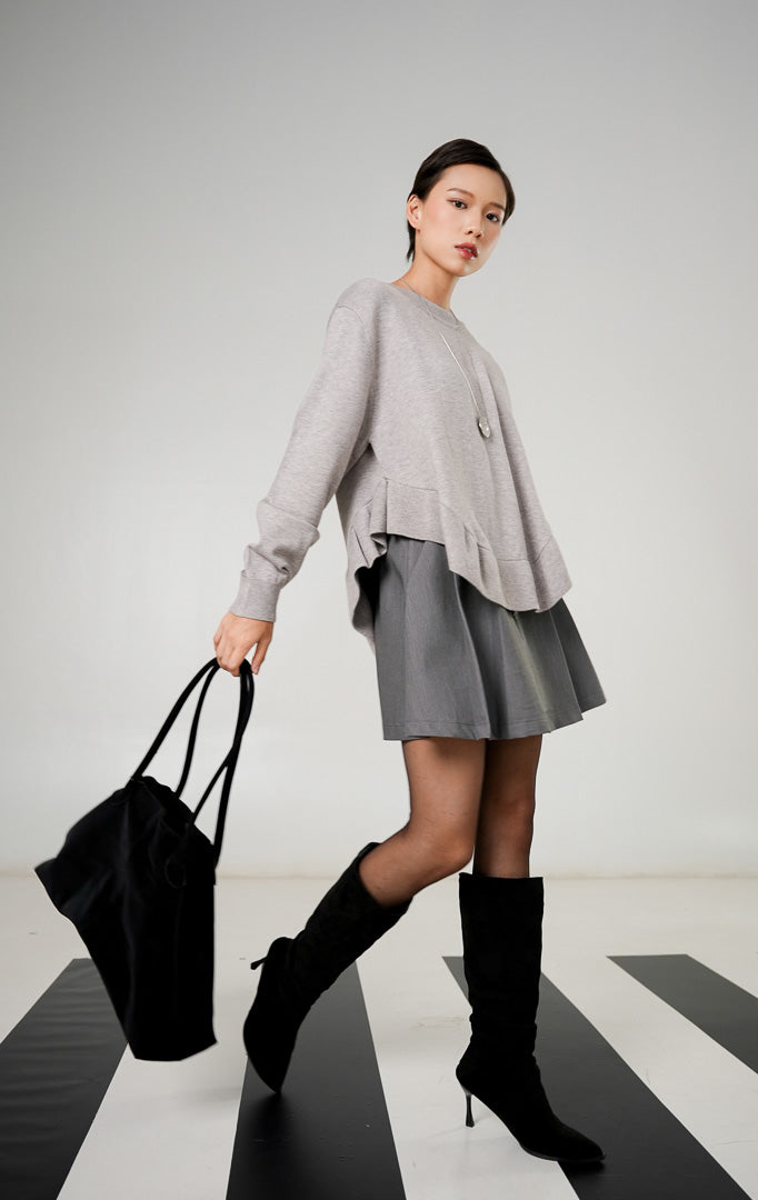Sweater rajut wanita lengan panjang warna abu abu muda (light grey) dengan detail hem ruffle bergelombang di bagian bawah dari This Is April.