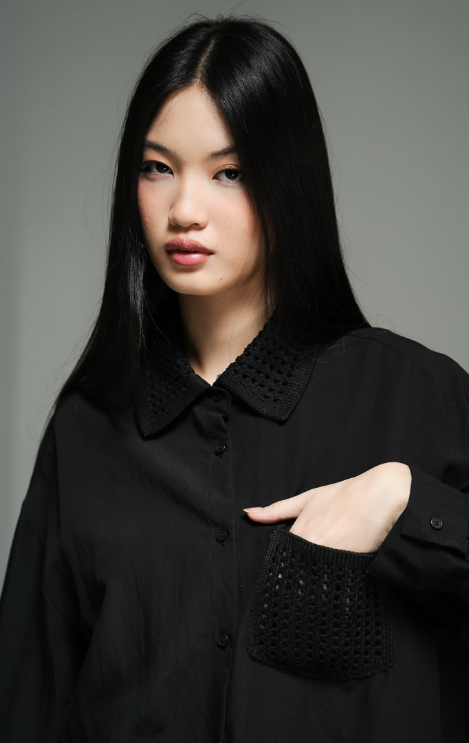 Kemeja wanita lengan panjang warna hitam (black chunky open-work crochet shirt top) Ripley Top dengan detail rajut tekstur terbuka yang unik, penutup kancing depan, serta saku fungsional yang fungsional.